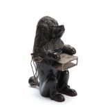 A 19TH CENTURY CARVED EBONISED SMOKERS COMPENDIUM formed as a dog with pipe holders to the sides and