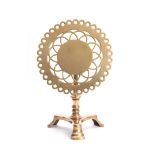 AN 18TH CENTURY BRASS TRIVET with pierced cut out circular tilt-top above a turned stem and tripod