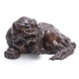 AN 18TH/19TH CENTURY CHINESE FINELY CAST AND FINISHED BRONZE FOO DOG depicted in a recumbent pose