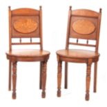 A PAIR OF ARTS AND CRAFTS OAK HALL CHAIRS with raised oval panel on the backrest and matching oval