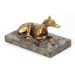 AN EARLY 20th CENTURY GILT BRONZE SCULPTURE modelled as a recumbent greyhound mounted on a marble