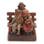 A CONTINENTAL CARVED POLYCHROME FIGURE of three children standing and seated on a bench 12cm wide