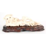 A LATE 19TH / EARLY 20TH CENTURY CHINESE CARVED IVORY SCULPTURE depicting a reclining dog with two