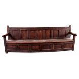 A RARE OVERSIZED 17TH CENTURY AND LATER JOINED OAK BOX SETTLE with an arcaded carved top rail,