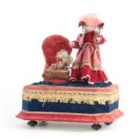 AN EARLY 20TH CENTURY MUSICAL AUTOMATON OF A GIRL PLAYING WITH A CAT the girl having a bisque