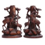 A PAIR OF LATE 19TH CENTURY SWISS CARVED CANDLESTICKS with mountain goats beneath tree trunks on