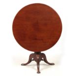 A GEORGE III MAHOGANY TILT TOP TABLE with a one-piece circular top, standing on gun barrel turned