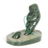 A 20TH CENTURY JADE INDUIT SCULTURE depicting a man fishing 9cm wide 8cm high.