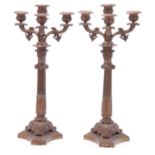 A PAIR OF REGENCY STYLE FOUR BRANCH BRASS CANDELABRA with reeded tapering columns mounted on a