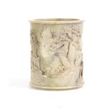 A 19TH CENTURY CHINESE PALE GREEN SOAPSTONE BRUSH POT the cylindrical body carved in high relief