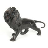 A JAPANESE MEIJI PERIOD PATINATED BRONZE SCULPTURE modelled as a lion with amber glass eyes,