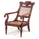 AN ANGLO INDIAN ROSEWOOD BERGERE ARMCHAIR having a reclining back, with pierced shaped headrest
