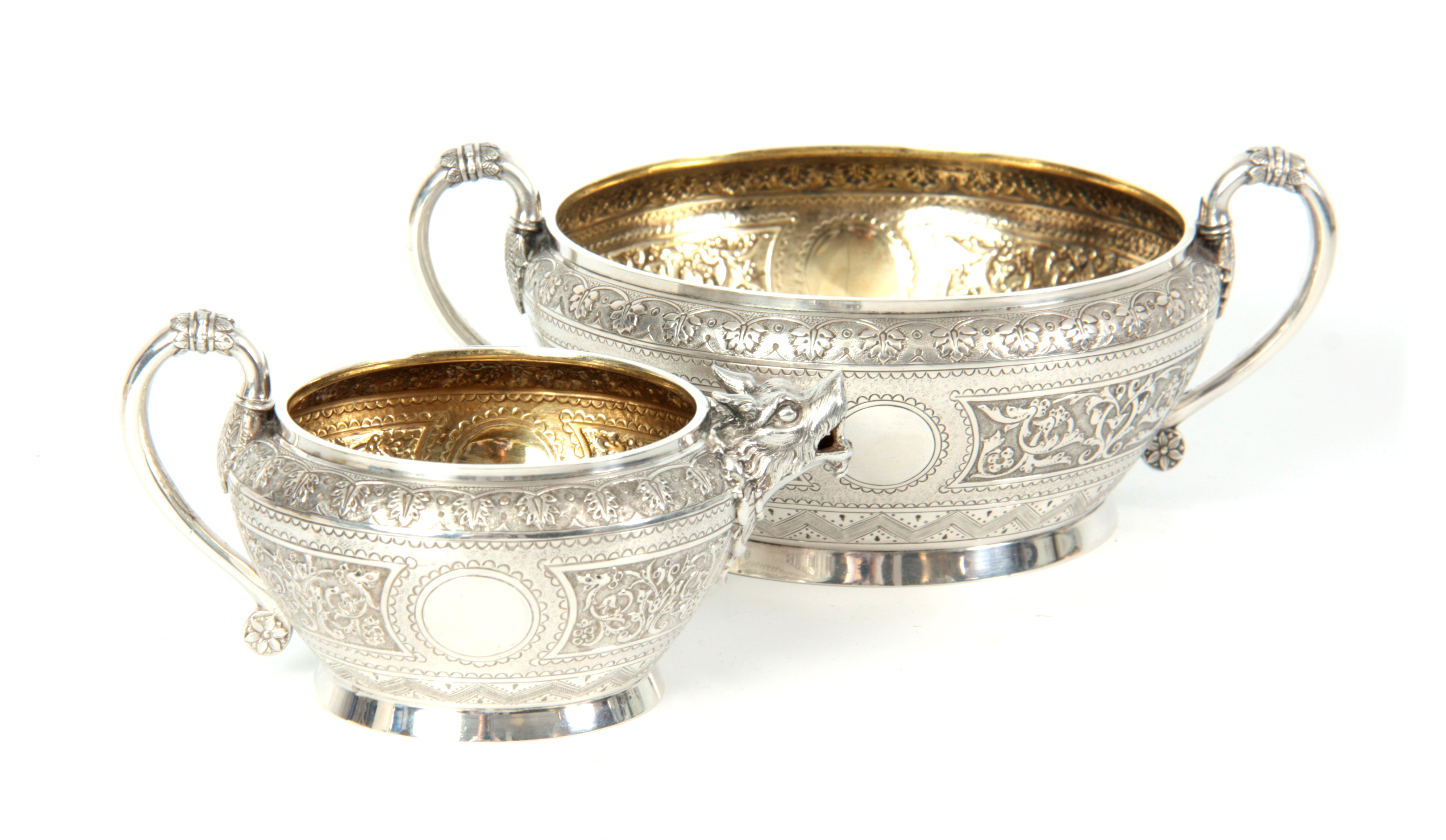 A VICTORIAN SILVER AND GILT CREAM JUG AND SUGAR BOWL having relief scroll-work panels and fine