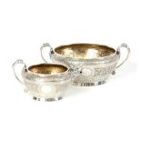 A VICTORIAN SILVER AND GILT CREAM JUG AND SUGAR BOWL having relief scroll-work panels and fine