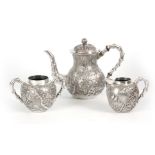 A LATE 19TH CENTURY CHINESE SILVER THREE PIECE TEA SET decorated in relief with birds among cherry