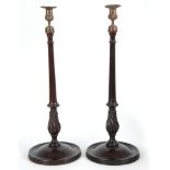 A TALL PAIR OF GEORGIAN STYLE MAHOGANY CANDLESTICKS having cast brass leaf work sconces and