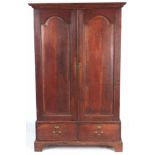 A MID 18TH CENTURY OAK HALL CUPBOARD with moulded cornice above a pair of arched fielded panel doors