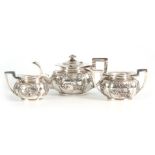 A 19TH CENTURY CHINESE THREE-PIECE SILVER TEA SERVICE of oblate panelled form with folded rims, each