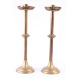 A PAIR OF LATE 19th CENTURY BRASS CHURCH CANDLESTICKS with circular bases and drip trays 64cm high