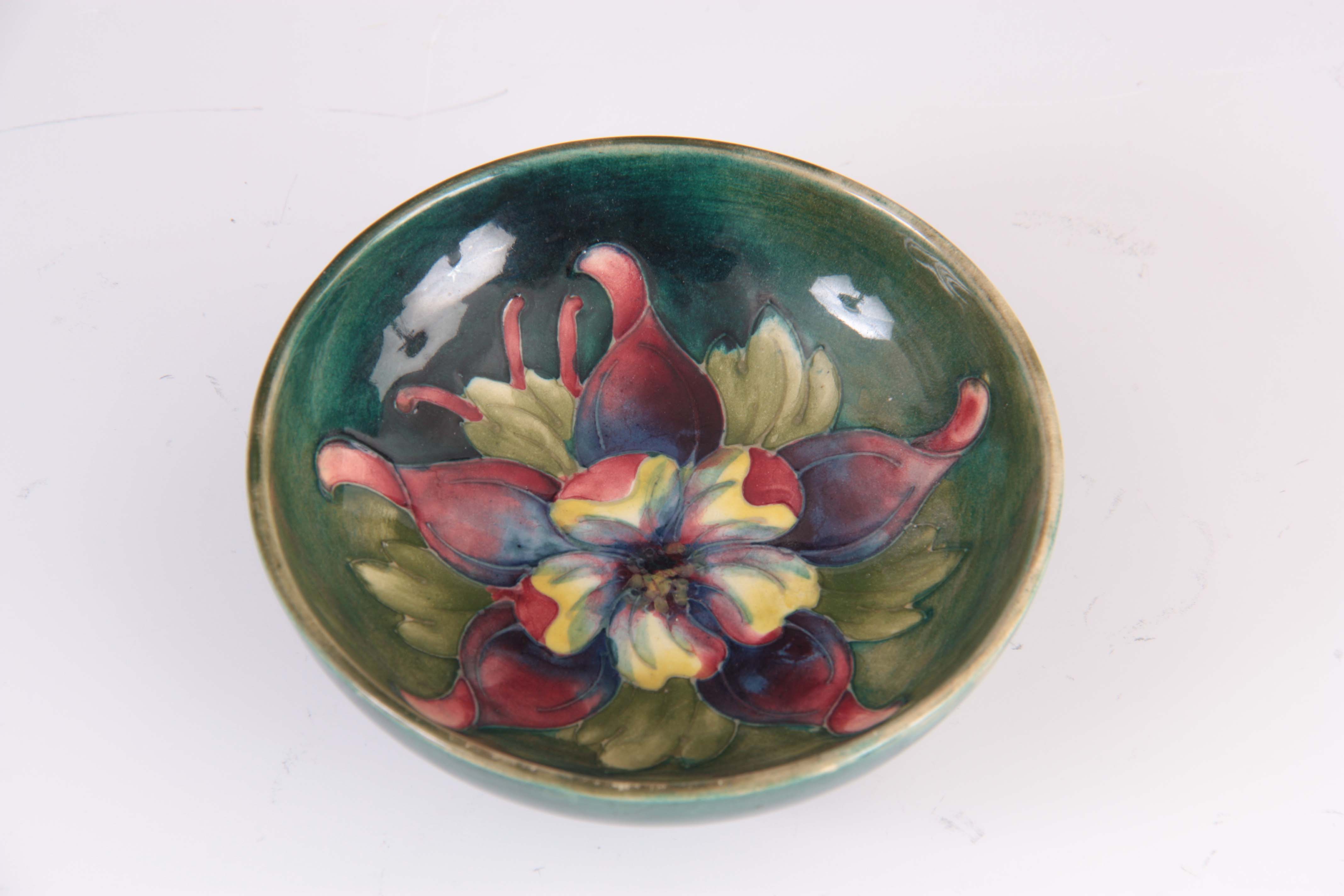 A CIRCA 1950S WALTER MOORCROFT COLUMBINE PATTERN FOOTED BOWL on a green ground 4cm high, 11.5 cm - Image 2 of 4