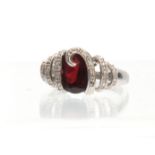 A 14ct WHITE GOLD RUBY AND DIAMOND RING having an oval brilliant-cut ruby entwined in a diamond-