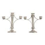 A PAIR OF PEWTER ARTS & CRAFTS CANDELABRA having a hammered finish and tapered stems on circular