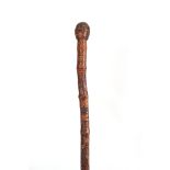 A 19th CENTURY JAPANESE BAMBOO WALKING CANE having a root handle, the stick carved all over with