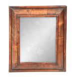 A 19TH CENTURY WILLIAM AND MARY STYLE WALNUT CUSHION FRAMED HANGING MIRROR with cross-grained