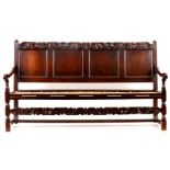 A CHARLES II JOINED OAK SETTLE with quadruple panelled back and bold leaf and shell carved top rail,
