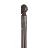 A 19TH CENTURY ROSEWOOD WALKING STICK of tapering form with carved figuratively pommel depicting a
