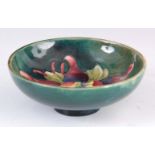 A CIRCA 1950S WALTER MOORCROFT COLUMBINE PATTERN FOOTED BOWL on a green ground 4cm high, 11.5 cm