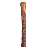 A 19th CENTURY CARVED FRUITWOOD WALKING CANE decorated to the handle a carved snake with black glass