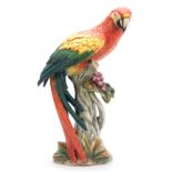 AN EARLY 20TH CENTURY ITALIAN POTTERY MACAW PARROT perched on blossoming tree - 46cm high