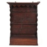AN 18TH CENTURY OAK AND FRUITWOOD HANGING SPOON RACK with moulded cornice above wavey edge shaped