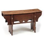 A LATE 17th CENTURY OAK BENCH with single plank top above a deep shaped frieze standing on two