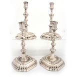 A SET OF FOUR CONTINENTAL CAST SILVER CANDLE STICKS having moulded square bases, octagonal stems,