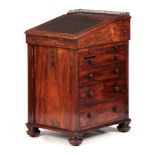 AN EARLY 19TH CENTURY ROSEWOOD DAVENPORT the top section with brass gallery and angled leather