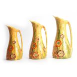 A SET OF THREE CARLTON WARE TAPERING JUGS with colourful relief moulded flowerhead and leaf work