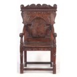 A 17TH CENTURY AND LATER OAK WAINSCOT CHAIR with eared shaped carved top rail centred by an arched