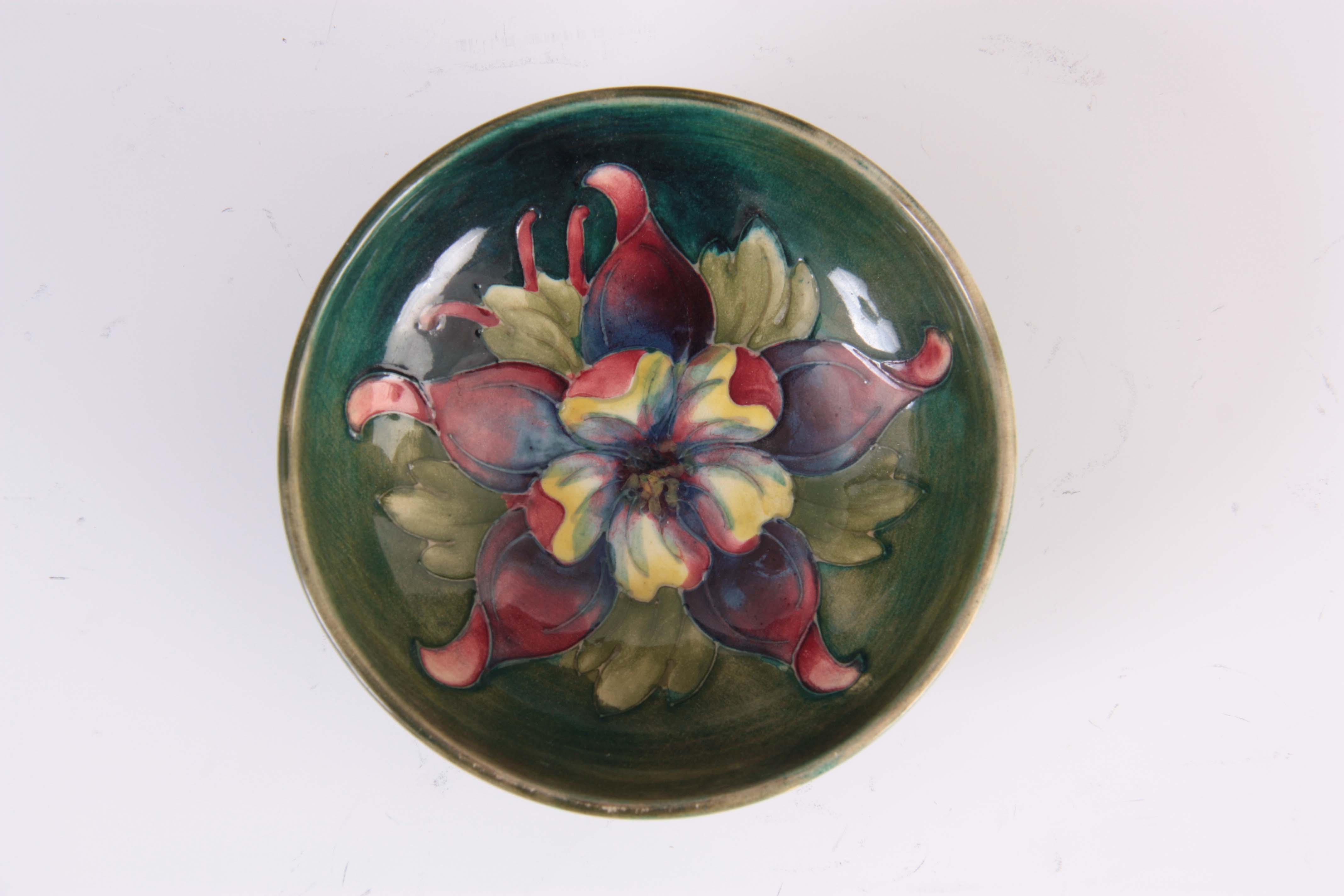 A CIRCA 1950S WALTER MOORCROFT COLUMBINE PATTERN FOOTED BOWL on a green ground 4cm high, 11.5 cm - Image 3 of 4