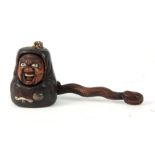 A MEIJI PERIOD JAPANESE TOBACCO POUCH AND PIPE HOLDER the carved wooden lid formed as a grotesque