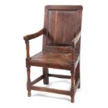 AN EARLY 18TH CENTURY OAK WAINSCOT CHAIR having fielded panel back with open arms and turned