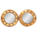 A PAIR OF SMALL REGENCY GILT GESSO CARVED CONVEX MIRRORS with ribbon and bobbin surrounds 31cm