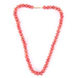 A CORAL BEAD NECKLACE with yellow metal mounts 50cm long beads average 1cm