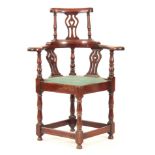 A GEORGE II WALNUT CORNER CHAIR with shaped back having pierced back splats raised by turned