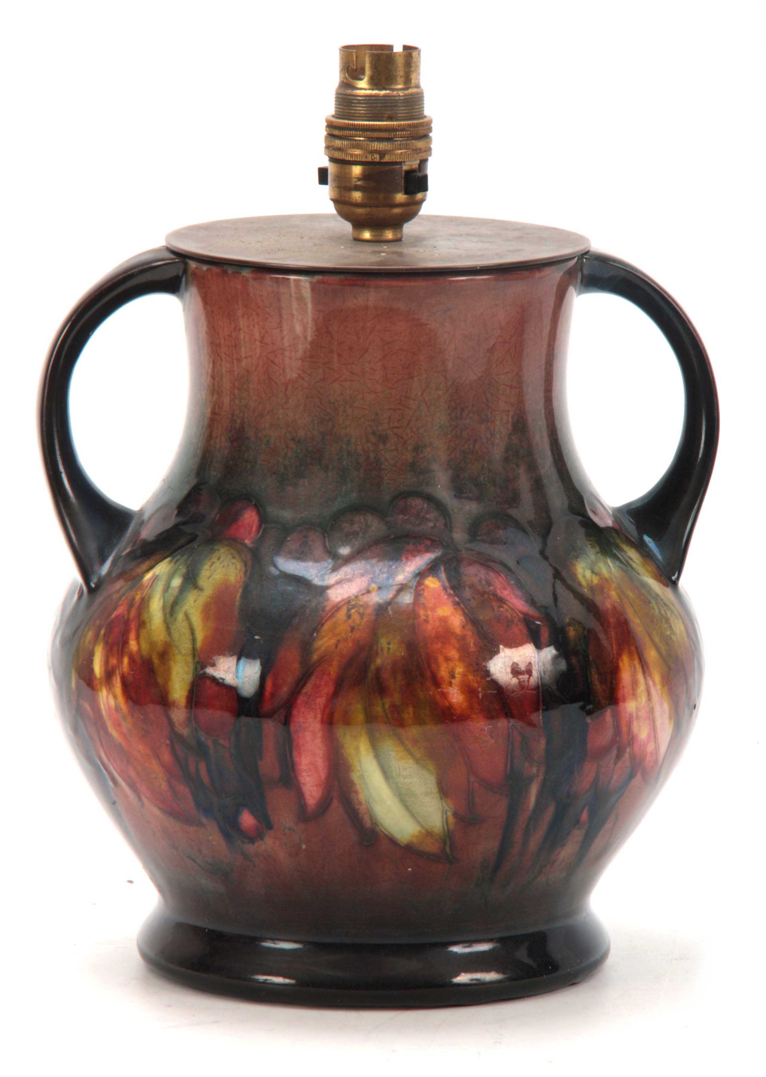 A 20TH CENTURY MOORCROFT LEAVES AND BERRY PATTERN TWIN HANDLED LAMP having flambe glaze with