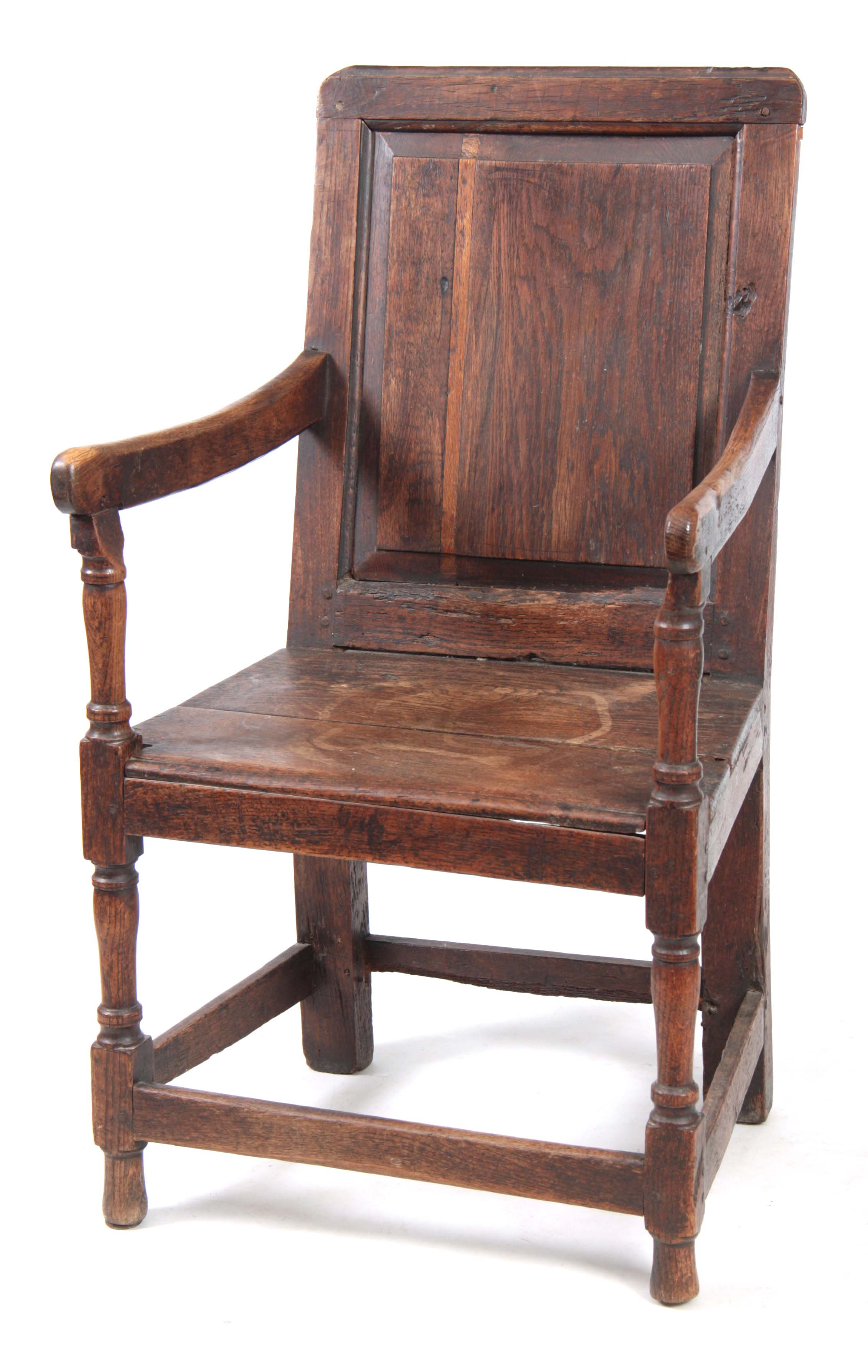 AN EARLY 18TH CENTURY OAK WAINSCOT CHAIR having fielded panel back with open arms and turned