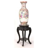 A 20th CENTURY CHINESE FAMILLE ROSE CANTON HALL VASE ON HARDWOOD STAND decorated with figures in a