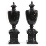A PAIR OF 20TH CENTURY BLACK VEINED MARBLE URNS with shaped tops and plinth bases 48cm high.