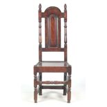 A LATE 17TH CENTURY OAK SIDE CHAIR with arched panelled back and turned column supports; panelled